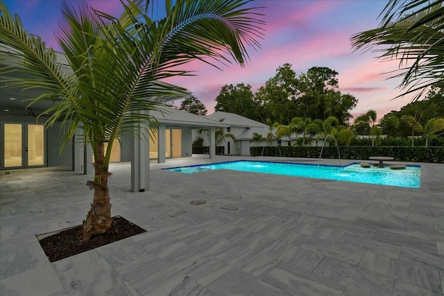 pool at dusk with a patio area and a fenced in pool