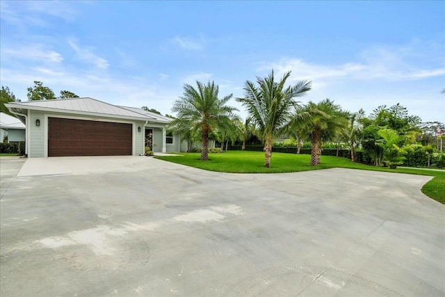 view of front of home featuring a garage, a front yard, metal roof, and driveway