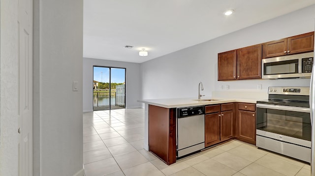 kitchen with sink, light tile patterned floors, kitchen peninsula, and appliances with stainless steel finishes