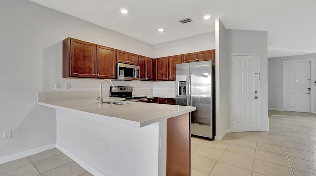 kitchen with appliances with stainless steel finishes, sink, light tile patterned flooring, and kitchen peninsula