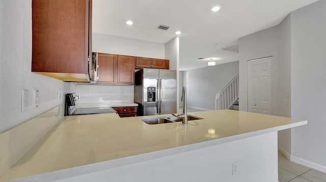 kitchen with kitchen peninsula, stainless steel fridge with ice dispenser, light tile patterned floors, stove, and sink