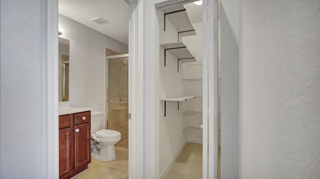 bathroom featuring toilet, an enclosed shower, tile patterned floors, and vanity