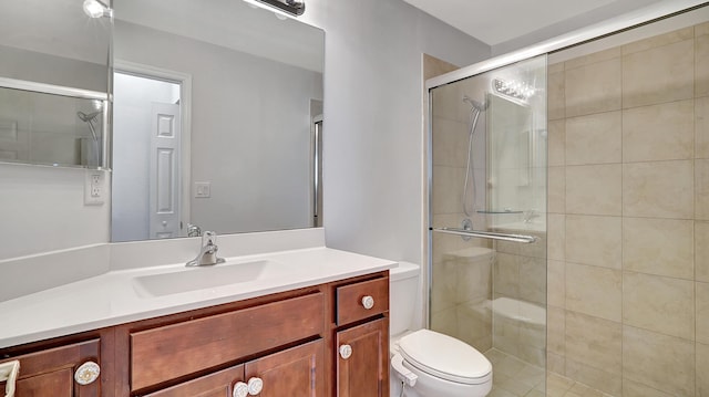 bathroom featuring toilet, vanity, and a shower with shower door