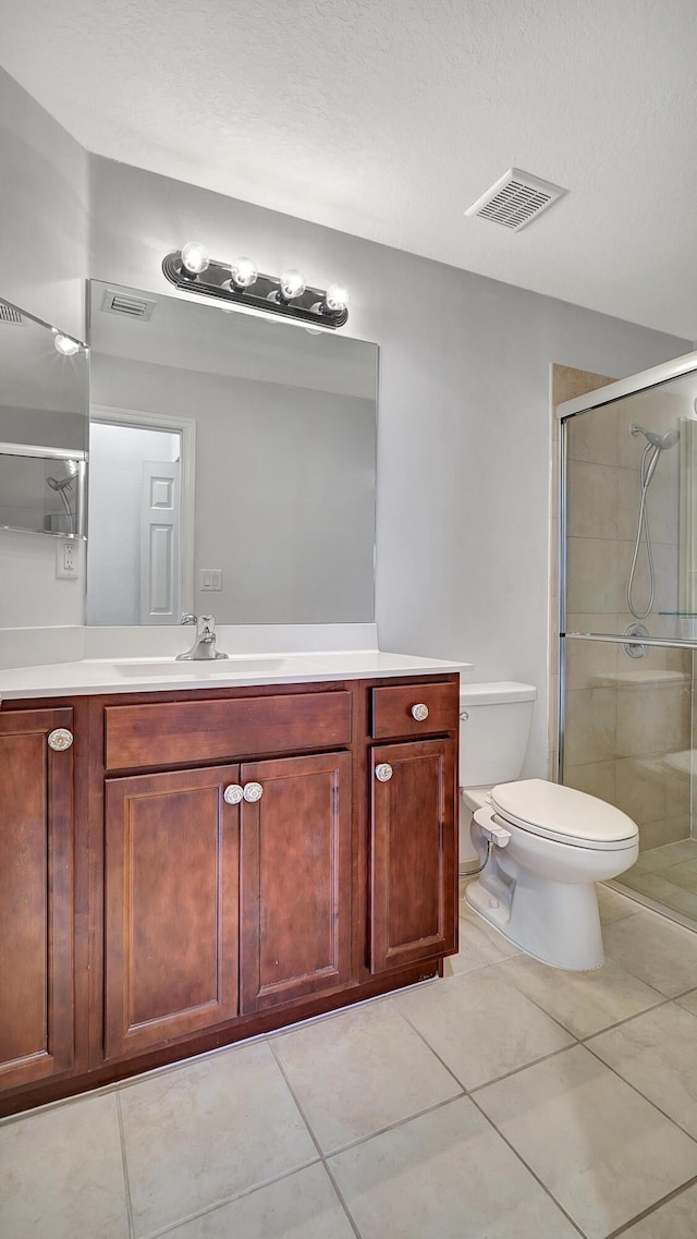 bathroom with toilet, a shower with door, tile patterned floors, and vanity