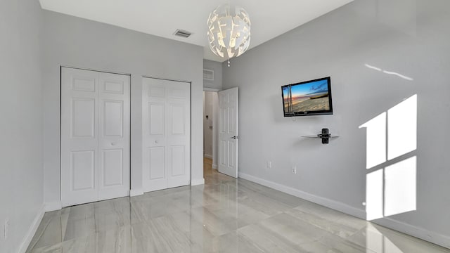 unfurnished bedroom with multiple closets and a chandelier