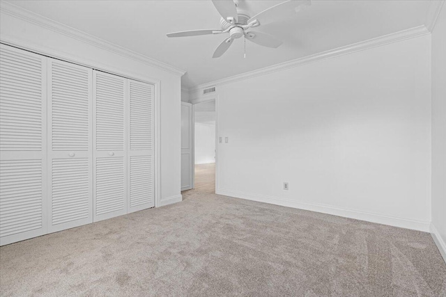 unfurnished bedroom featuring a closet, light colored carpet, ceiling fan, and ornamental molding