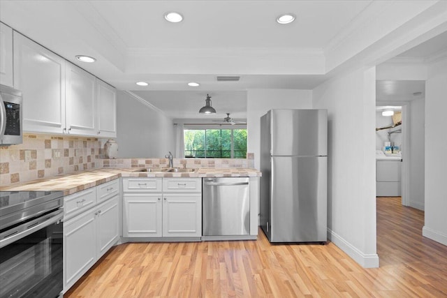 kitchen featuring white cabinets, appliances with stainless steel finishes, tasteful backsplash, and crown molding