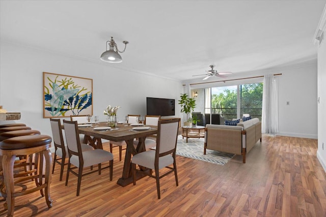 dining space featuring ceiling fan, wood-type flooring, and ornamental molding