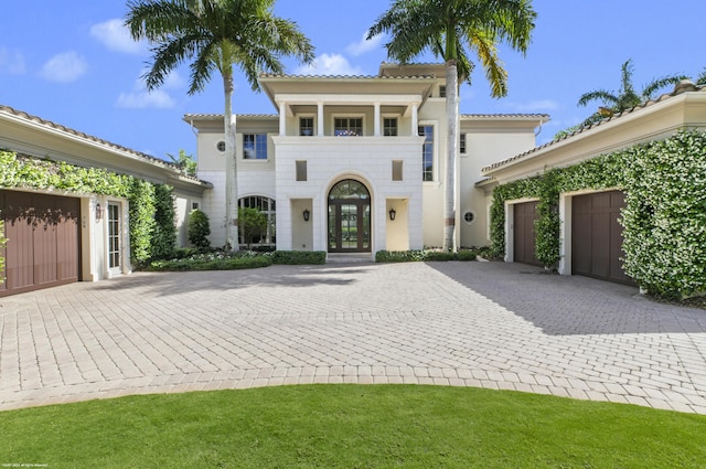 mediterranean / spanish house featuring a front lawn, french doors, and a balcony