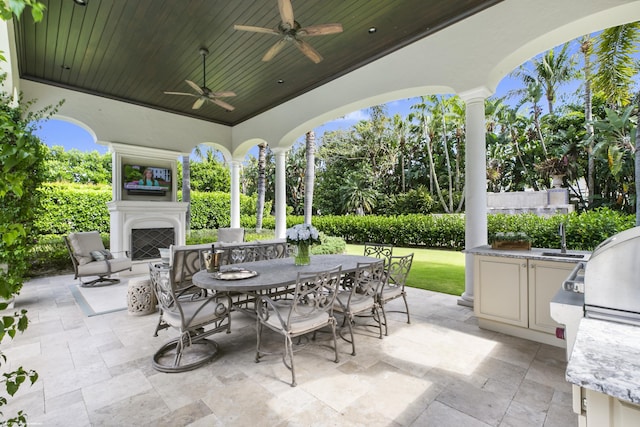 view of patio featuring ceiling fan, area for grilling, and an outdoor fireplace