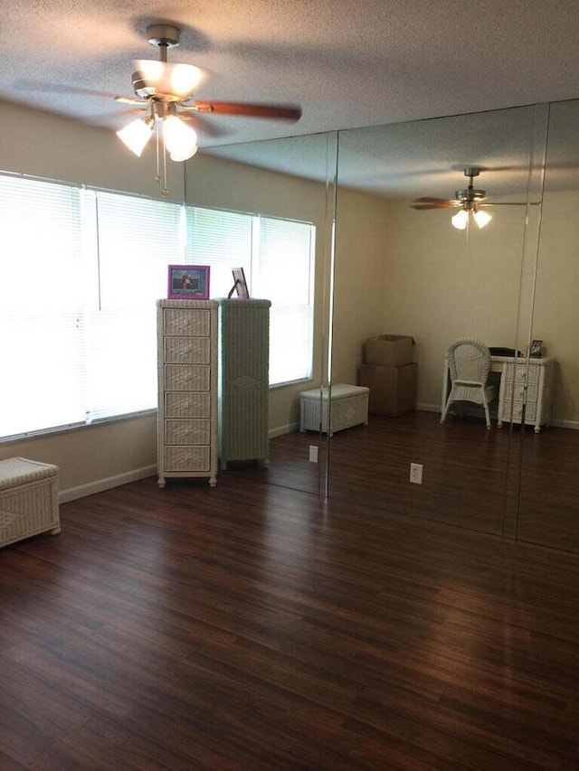 unfurnished living room featuring a textured ceiling, dark hardwood / wood-style floors, and ceiling fan