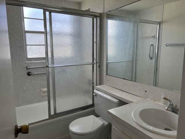 full bathroom featuring vanity, toilet, and shower / bath combination with glass door