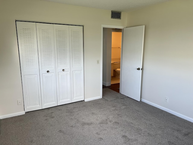 unfurnished bedroom with a closet and dark colored carpet