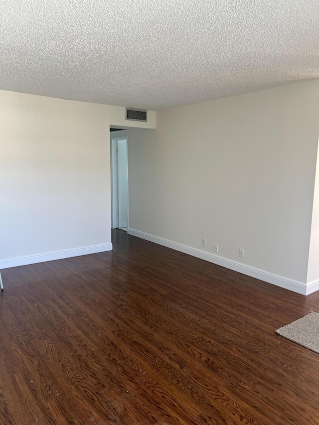 unfurnished room with a textured ceiling and dark hardwood / wood-style floors