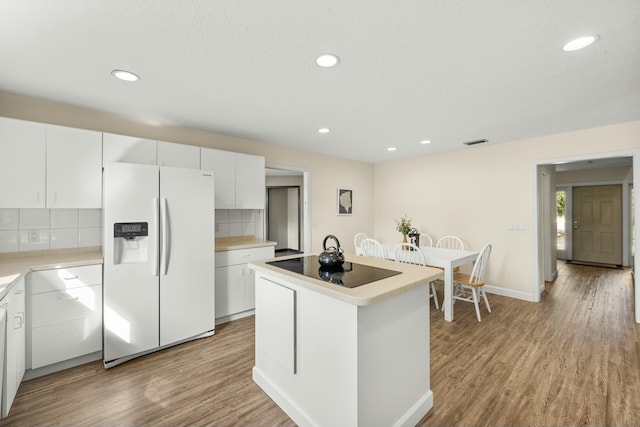 kitchen featuring white cabinetry, white fridge with ice dispenser, and tasteful backsplash