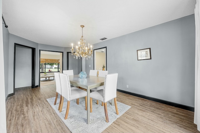 dining space featuring a notable chandelier and light wood-type flooring