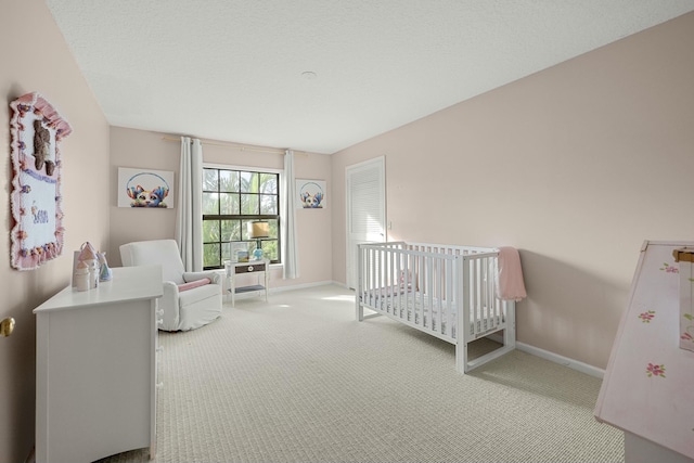 bedroom with carpet flooring, a textured ceiling, and a crib