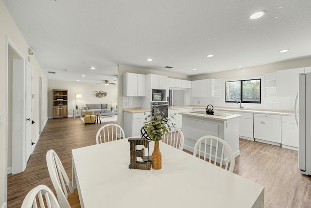 dining space featuring ceiling fan, light hardwood / wood-style floors, sink, and a textured ceiling