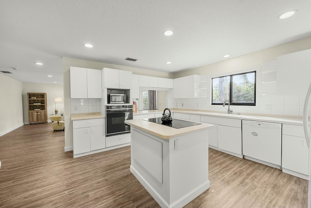 kitchen with white cabinetry, sink, backsplash, a kitchen island, and black appliances