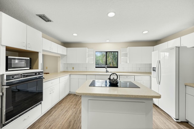 kitchen with white cabinetry, a center island, and black appliances