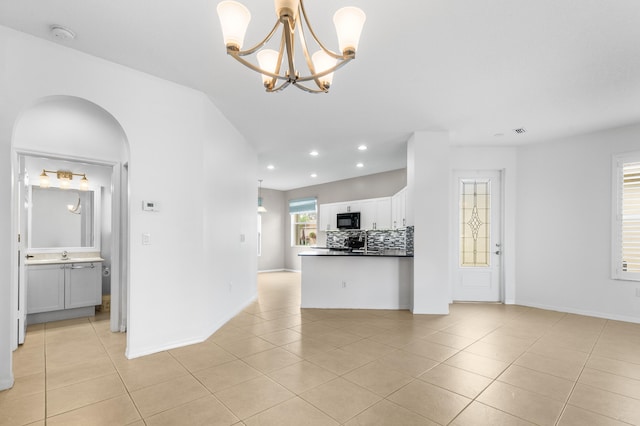 kitchen featuring decorative backsplash, a notable chandelier, white cabinets, hanging light fixtures, and light tile patterned flooring