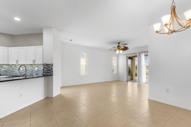 unfurnished living room with sink, light tile patterned floors, and ceiling fan with notable chandelier