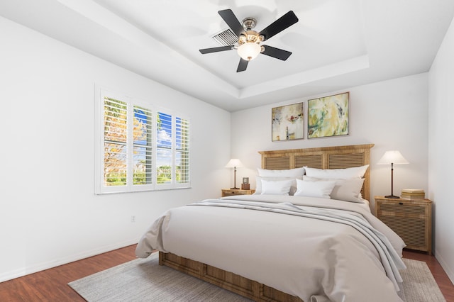 bedroom featuring a raised ceiling, ceiling fan, and hardwood / wood-style flooring