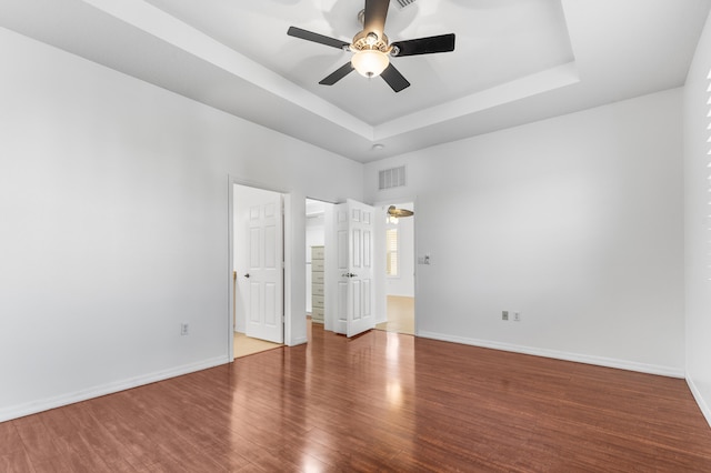 unfurnished bedroom featuring hardwood / wood-style floors, ceiling fan, and a tray ceiling