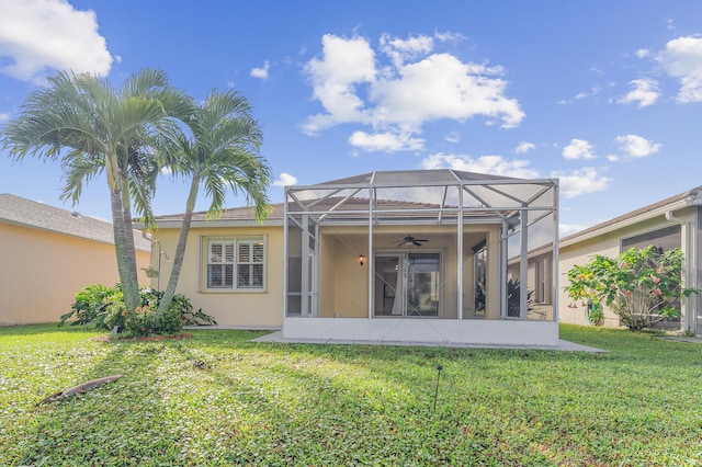 back of house with a lawn, glass enclosure, and ceiling fan