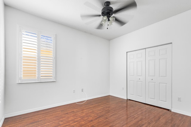 unfurnished bedroom featuring multiple windows, a closet, dark hardwood / wood-style floors, and ceiling fan