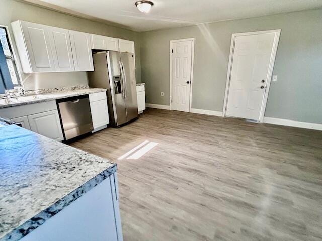 kitchen with white cabinets, appliances with stainless steel finishes, light wood-type flooring, and sink