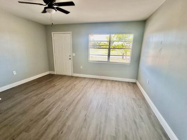 empty room with baseboards, ceiling fan, and wood finished floors