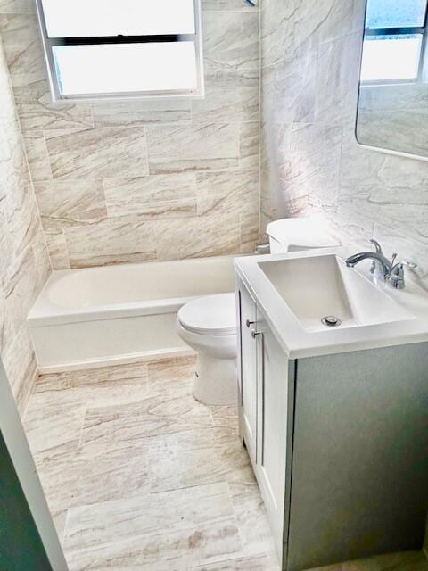 full bathroom featuring vanity, shower / washtub combination, toilet, and tile walls