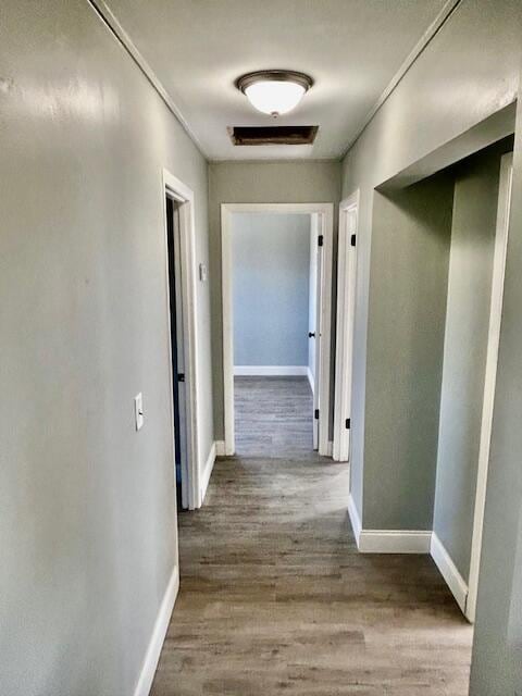 corridor featuring baseboards and wood finished floors