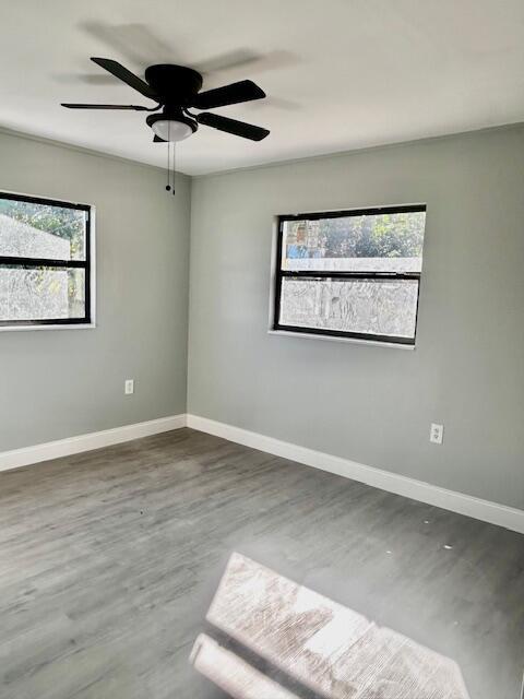 empty room with dark hardwood / wood-style floors and ceiling fan