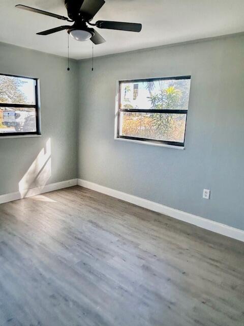 unfurnished room featuring wood-type flooring, ceiling fan, and a healthy amount of sunlight