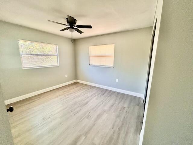 spare room with a ceiling fan, baseboards, and wood finished floors