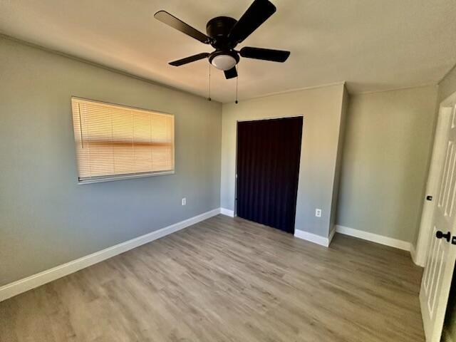 unfurnished bedroom with a ceiling fan, baseboards, and wood finished floors
