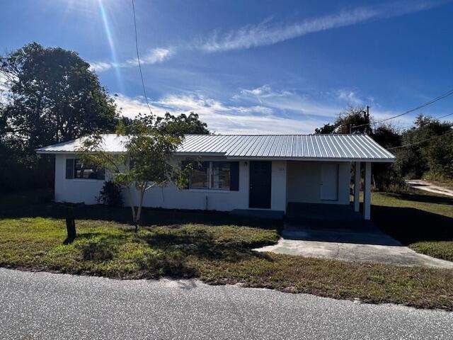 single story home with a front lawn and a carport