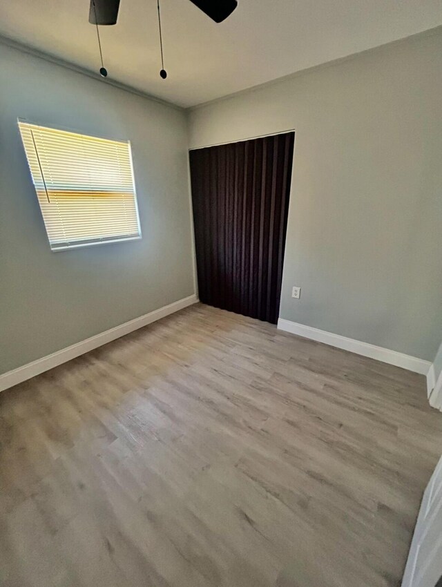 spare room with baseboards, ceiling fan, and wood finished floors