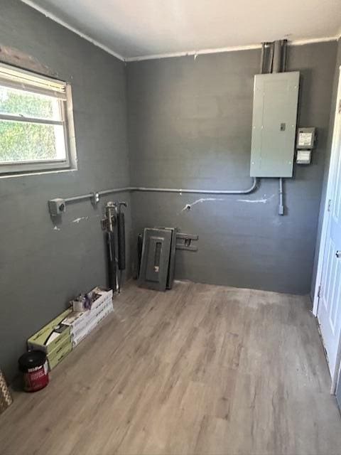 clothes washing area with ornamental molding, wood finished floors, and electric panel