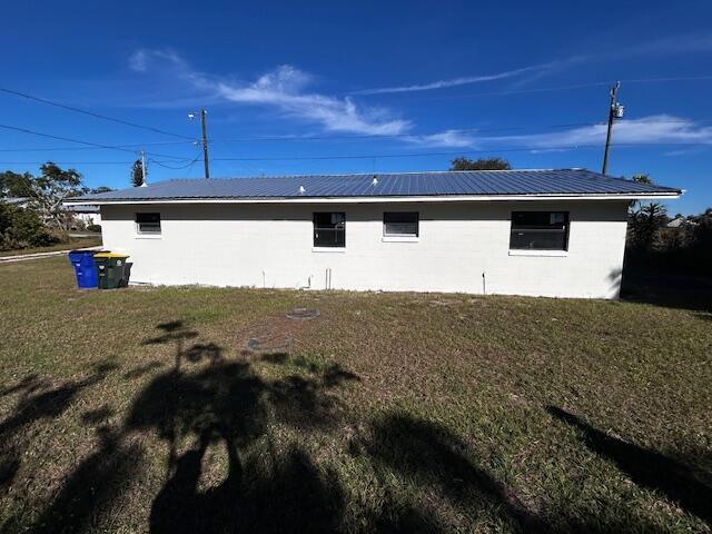 view of side of home featuring a lawn and metal roof