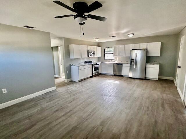 kitchen with white cabinets, appliances with stainless steel finishes, and hardwood / wood-style floors