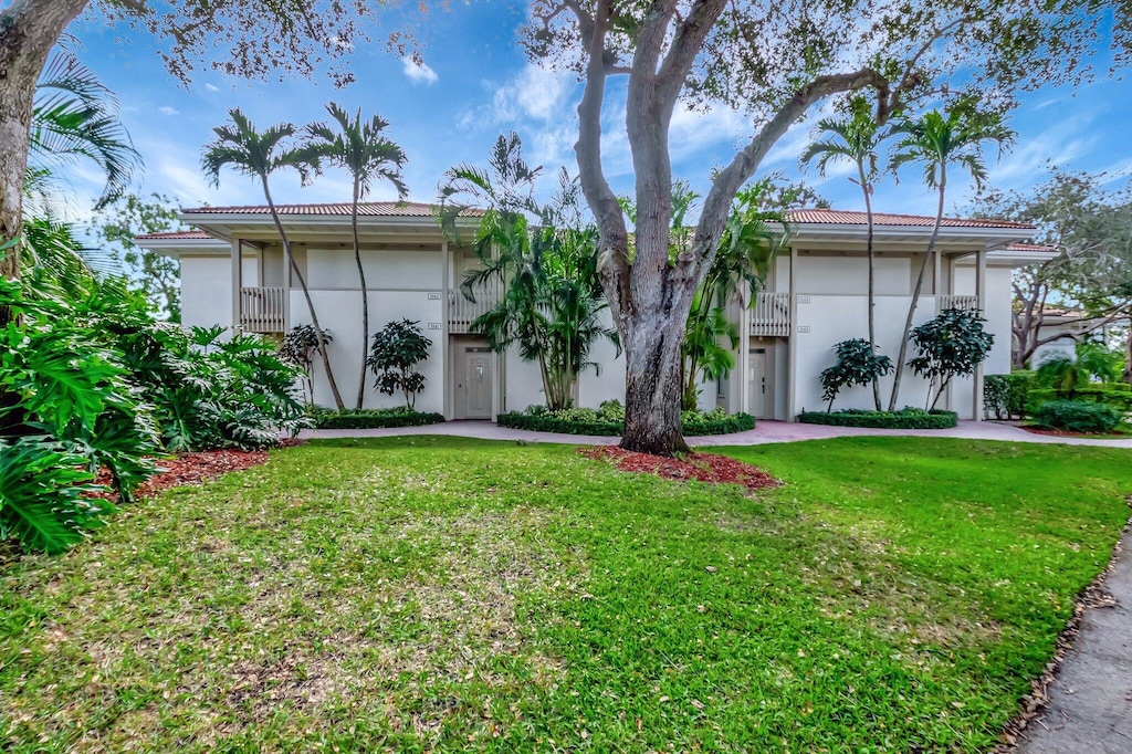 ranch-style home featuring a balcony and a front lawn