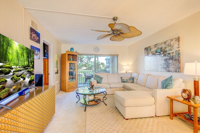 living room with a textured ceiling, light colored carpet, and ceiling fan