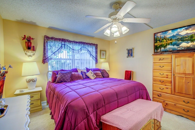 bedroom with a textured ceiling, light colored carpet, and ceiling fan