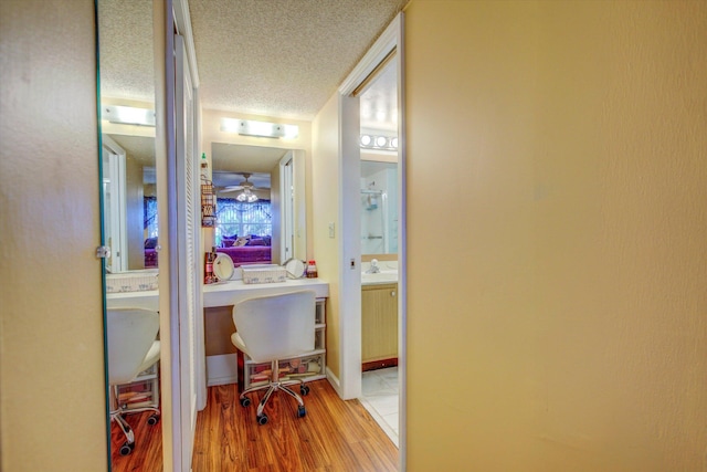 hall featuring sink, a textured ceiling, and light hardwood / wood-style flooring