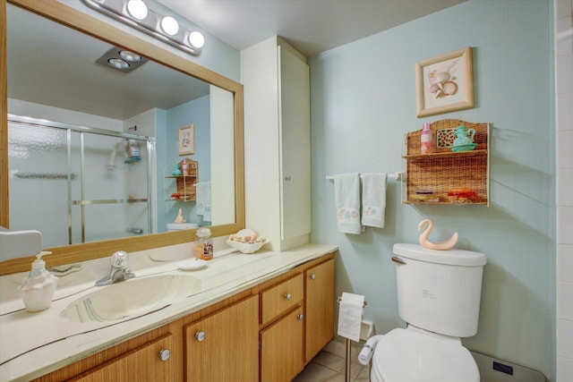 bathroom with toilet, tile patterned flooring, a shower with door, and vanity