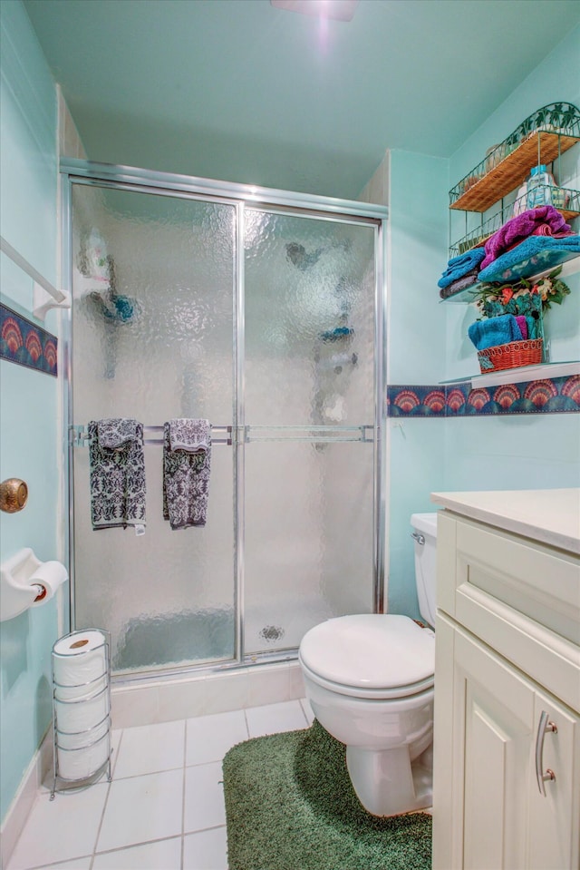 bathroom with vanity, toilet, tile patterned floors, and a shower with shower door