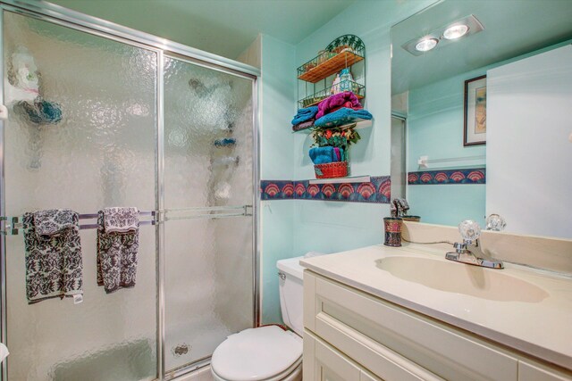 bathroom with toilet, an enclosed shower, and vanity